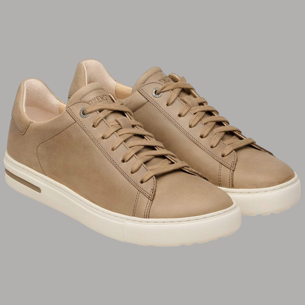 Paio di sneakers in pelle tabacco con lacci e suola bianca