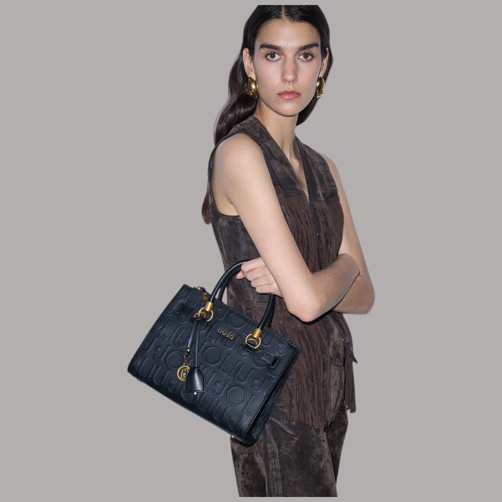 Borsa a mano piccola nera con tracolla corta, logo a rilievo e charm dorato.