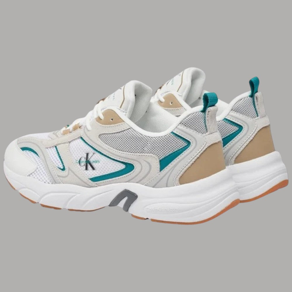 Sneaker bianca con tallone beige, dettagli verde petrolio e suola spessa ammortizzata.