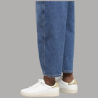 Sneaker bianche in pelle con bordo oro al tallone indossate con pantaloni blu