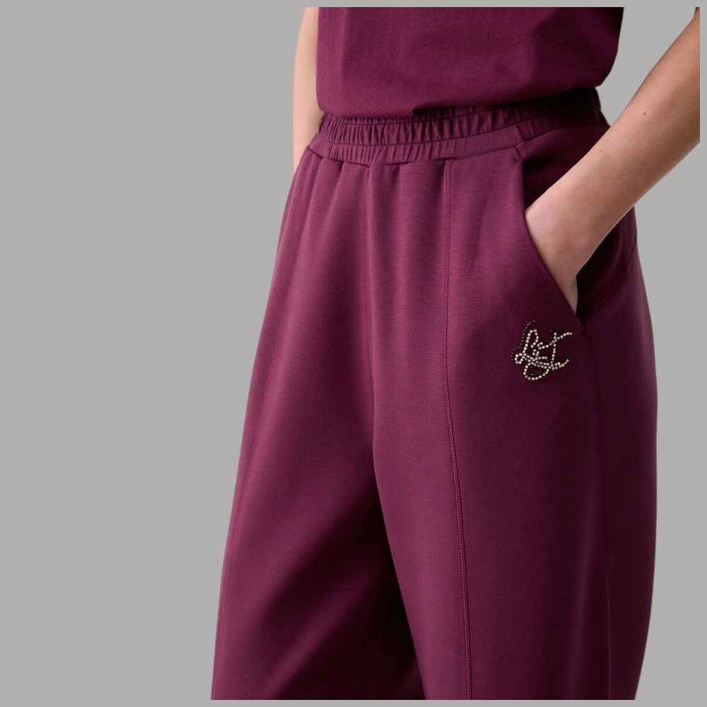 Pantaloni Liu Jo in scuba melanzana, dettaglio del logo applicato e della tasca laterale