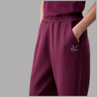Pantaloni Liu Jo in scuba melanzana, dettaglio del logo applicato e della tasca laterale