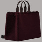 Borsa tote bordeaux in pelliccia con due scomparti e manici in tinta.