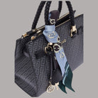 Borsa a mano con zip e manici intrecciati, foulard azzurro e charm pendenti