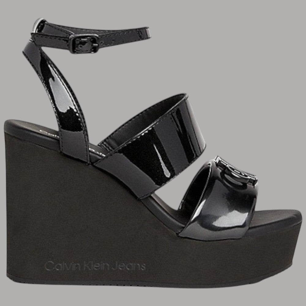 Sandalo con zeppa Calvin Klein Jeans nero lucido, fibbia alla caviglia.