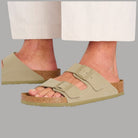 Ciabatte khaki con fibbie ai cinturini indossate con gambe scoperte