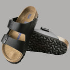Ciabatte Birkenstock Arizona SFB nere con fodera beige e suola con intagli.