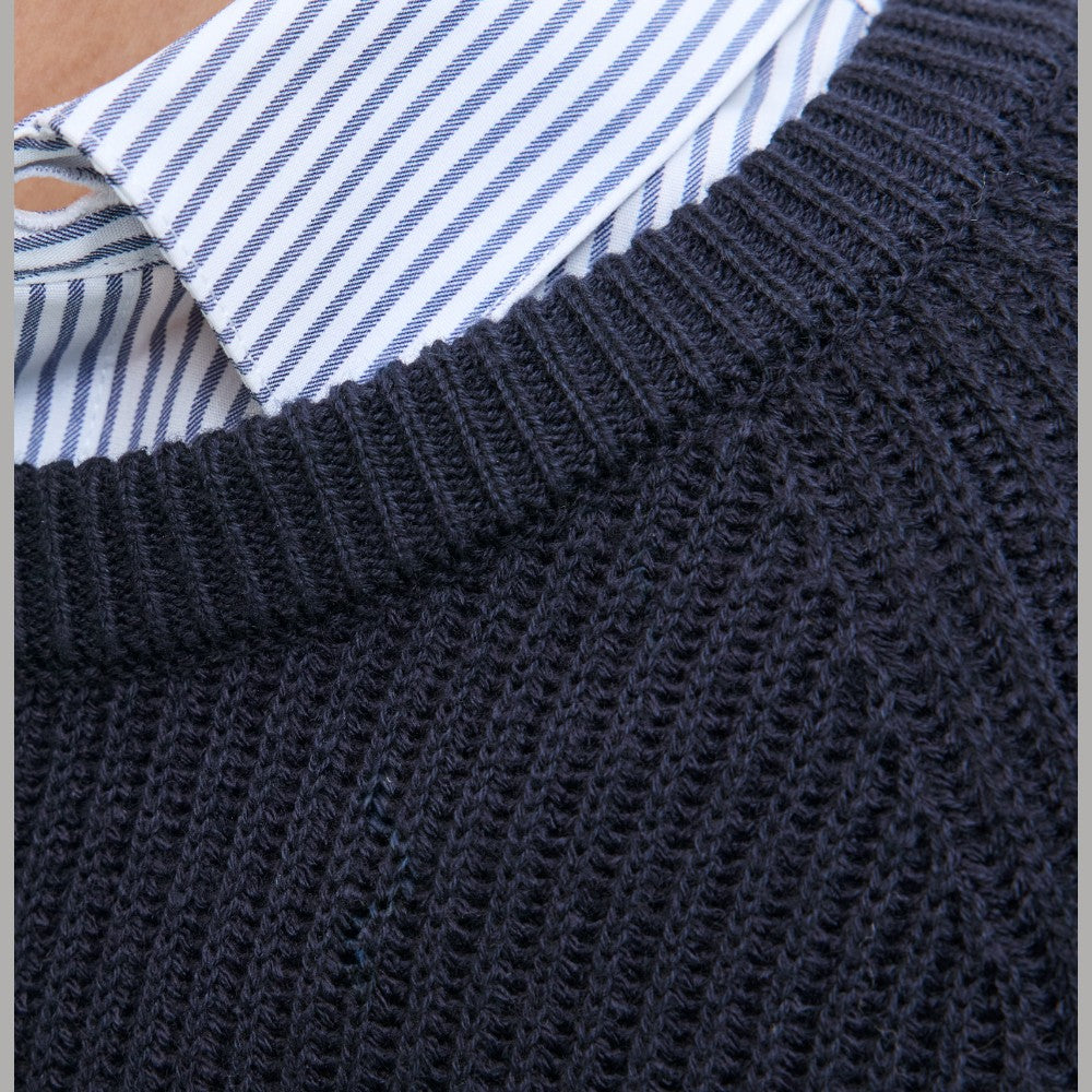 Collo e spalle di maglione a coste blu scuro con camicia a righe sotto.