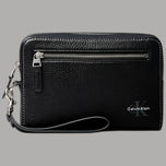 Pochette Calvin Klein nera con logo signature, cinturino da polso rimovibile, texture saffiano