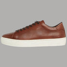 Sneakers in pelle marrone con lacci scuri e suola bianca