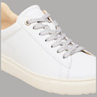 Vista laterale sneaker bianche in pelle con lacci grigi e occhielli oro