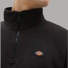 Dettaglio felpa mezza zip: colletto alto e logo Dickies su tessuto scuro
