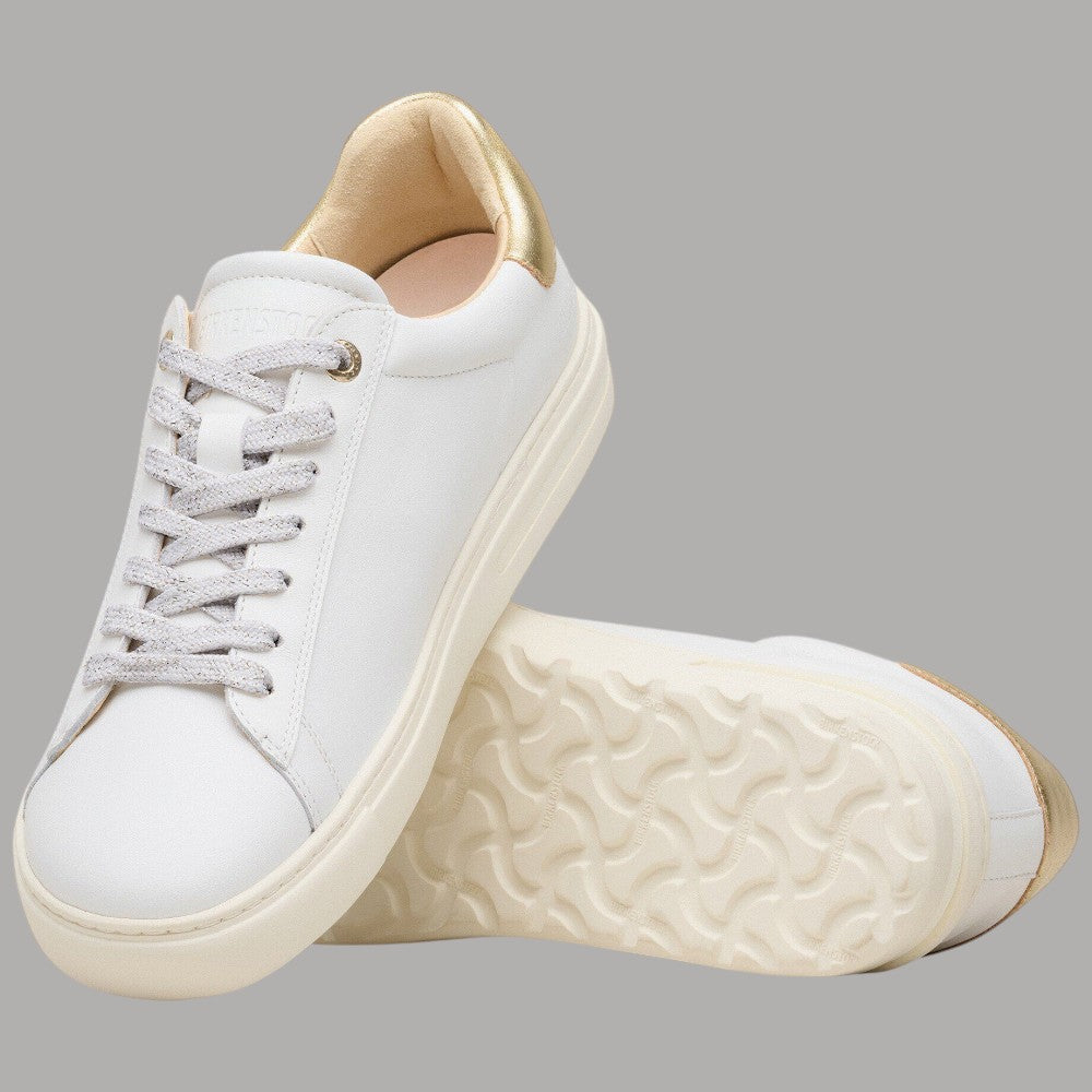 Sneaker bianca in pelle con interno beige e suola con rilievi, dettagli oro al tallone