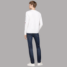 Modello indossa T-shirt manica lunga bianca Prodotti di Classe con logo Tommy Hilfiger ricamato sulla manica